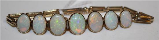 Yellow metal and opal cabochon bracelet, with 7 graduated stones in rubover settings